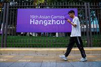 A person walks past a poster of Asian Games in Hangzhou
